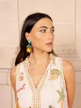 Vestido largo color crema con estampado de flores y corazones en tonos azules, naranjas y amarillos. Tiene cuello en V con ribete azul y corte imperio con falda escalonada.