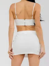 Set compuesto por top de tirantes finos con apliques de pedrería y mini falda blanca elastizada con bolsillos laterales tipo cargo.