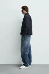 Sobrecamisa de corte regular fit en tejido técnico negro resistente al agua, con cuello estilo bomber en rib elástico, cierre frontal de cremallera y bolsillos plastrón con solapa en la cadera.