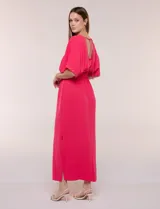 Vestido largo amarillo de corte fluido con escote en V, mangas cortas amplias y apliques de tachas en el escote y puños. Posee cintura elastizada fruncida y falda larga con tajos laterales en el ruedo.