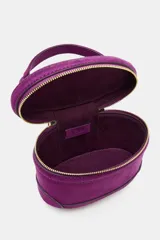 Bolso tipo vanity de estructura rígida en color fucsia, con acabado aterciopelado. Presenta un asa de mano superior, cierre de cremallera metálica dorada con doble tirador y correa bandolera ajustable y extraíble.