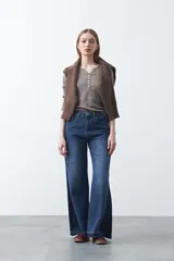 Remera de manga larga color beige, confeccionada en algodón, con escote en V y cartera corta de botones blancos.