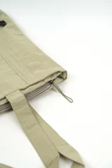 Bolso de nylon color beige, estilo tote bag, con asas de hombro, cierre superior y detalles de cordones ajustables en la parte inferior.
