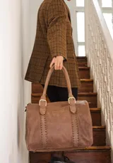 Bolso de mano tipo shopper marca Amadea, confeccionado en cuero con acabado desgastado. Presenta detalles de costuras decorativas verticales, correas con hebillas metálicas doradas y logo grabado al frente.