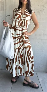 Vestido largo color blanco con estampado abstracto en marrón, con escote en V y corte escalonado.