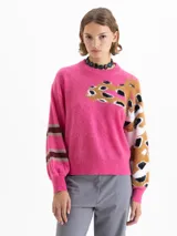 Sweater de punto color fucsia, con cuello redondo. Presenta un diseño de manchas abstractas en tonos marrón, negro y blanco en el frente y en la manga derecha. La manga izquierda tiene un diseño de rayas horizontales en tonos marrón y gris.