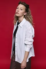 Camisa de manga larga color blanco, con cuello clásico y cierre frontal de botones de nácar. Presenta un corte cómodo y versátil.