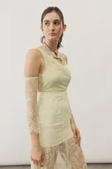 Vestido largo blanco de encaje con diseño asimétrico, tirante fino en un hombro y falda transparente.