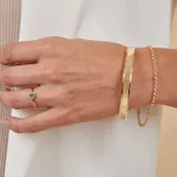Esclava rígida de oro 18k con acabado satinado y diseño de cinta plana. Presenta una textura fina en su superficie y un diseño minimalista.