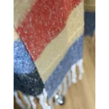 Bufanda rectangular de tejido grueso con diseño de cuadros en tonos azul, naranja, gris y beige, terminada con flecos en los extremos.