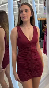 Vestido corto bordó con brillos, escote en V pronunciado, tirantes anchos y diseño fruncido en el centro.