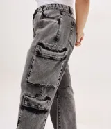 Pantalón de jean con corte recto y efecto desteñido, caracterizado por sus bolsillos cargo funcionales en los laterales y pences en las rodillas. Presenta un diseño utilitario y moderno con cierre frontal y bolsillos clásicos.