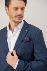 Saco de vestir con diseño de espiga en color marrón, confeccionado en mezcla de lana y seda. Presenta solapas clásicas, cierre frontal de dos botones y bolsillos laterales con solapa.
