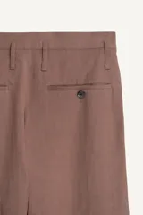 Pantalón de corte relajado confeccionado en tejido fluido con mezcla de viscosa y lino. Presenta un diseño cruzado en la cintura con cierre de cremallera, botón y trabilla ajustable. Cuenta con bolsillos laterales y bolsillos traseros de vivo con botón.