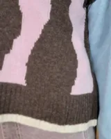 Chaleco tejido de punto con diseño abstracto en bloques de color marrón y turquesa, con cuello redondo y terminaciones acanaladas.