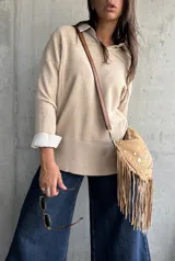 Sweater de punto en color beige, con cuello redondo, mangas largas con puños acanalados y diseño de corte holgado.