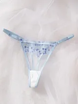 Conjunto de lencería de tul transparente color celeste, con delicado bordado floral en tonos celestes y blancos. Incluye un corpiño con aro y tirantes regulables, y una tanga regulable con tiras finas.