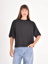 Remera de corte boxy y holgado, con cuello redondo y mangas cortas, en color negro liso.