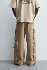 Pantalón cargo de denim lavado negro, corte relajado y tiro medio. Presenta múltiples bolsillos cargo con solapa y detalle de cierre en las perneras, además de bolsillos de vivo traseros. El bajo es ajustable con trabilla.