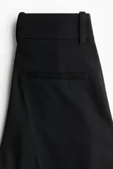Pantalón sastrero de tiro alto con pinzas, corte holgado y piernas rectas. Cuenta con cierre frontal oculto, bolsillos laterales y bolsillos traseros decorativos.