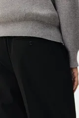 Pantalón de corte relajado color negro, con cintura elástica, cierre frontal con botón y cordón de ajuste oculto. Presenta piernas con raya marcada, bolsillos laterales al bies y bolsillos traseros ribeteados con botón.