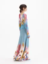 Pollera larga de tiro alto con calce evasé, confeccionada en tejido celeste con cintura elastizada lisa y estampado floral multicolor en el ruedo.