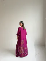 Vestido largo magenta con estampado floral en la parte inferior, de corte holgado y manga larga.