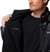Campera de polar con textura tipo corderito, con estampado camuflado en tonos grises y negros. Presenta cierre frontal completo, cuello alto y un bolsillo frontal en el pecho con cierre y logo de la marca.