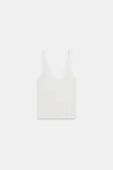Top de punto canalé en color beige, con escote en pico adornado con una delicada aplicación de encaje blanco y tirantes anchos.