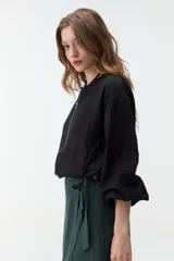 Campera negra corta con cierre frontal y mangas anchas.