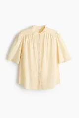 Blusa oversize en mezcla de algodón y viscosa, color amarillo claro, con cuello mao, botonadura frontal y mangas cortas abullonadas con terminación en broderie.