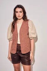 Chaleco sin mangas de color marrón, con diseño acolchado y bordados florales en toda la superficie. Presenta un corte recto y terminaciones con ribetes al tono.