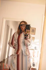Camisa de popelina a rayas multicolor con diseño de mangas abullonadas, cuello clásico y detalles de cordones cruzados estilo corsé en los laterales.