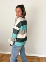 Remera de manga larga en tejido liviano con diseño de rayas anchas en tonos fucsia, gris y crudo. Corte recto y cómodo con bolsillo delantero.