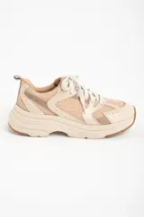 Zapatilla deportiva de mujer con plataforma gruesa, combinando paneles de malla transpirable color beige claro y superposiciones en tonos rosa viejo y crema. Cordones blancos y suela de goma color caramelo.