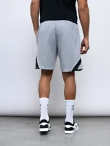 Bermuda deportiva negra de algodón y poliéster, con cintura elástica ajustable con cordón, bolsillos laterales y detalle de recortes geométricos en gris en los laterales. Logo de la marca bordado en la pierna izquierda.