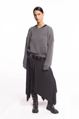 Buzo de punto inglés grueso en color gris melange, de corte amplio con hombros caídos y mangas largas, con sutil bordado de la marca en el pecho.