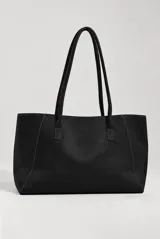 Cartera tipo tote de color marrón oscuro, con diseño estructurado, costuras en contraste y doble asa de hombro. Cuenta con un detalle de tira con hebilla metálica dorada y un colgante decorativo en la parte frontal.