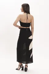 Top crop negro con tirantes finos que se cruzan en el cuello y detalle fruncido en el centro del busto.