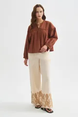 Pantalon ancho de algodón en color beige con detalle de bordado decorativo en el ruedo.