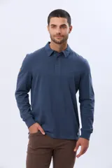 Remera polo de manga larga confeccionada en tejido jersey, con cuello clásico y cierre frontal de tres botones. Presenta un diseño liso con un pequeño logo bordado en el pecho y una etiqueta decorativa en el ruedo.