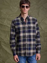 Camisa de manga larga con estampado de cuadros en tonos azul, verde oliva y beige. Presenta cuello clásico, cierre frontal con botones y un bolsillo en el pecho.