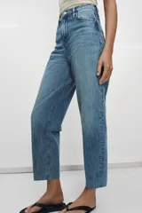 Jeans de tiro alto con corte tapered y largo al tobillo. Presenta cinco bolsillos, trabillas en la cintura, cierre frontal con cremallera y botón, y detalle de raya planchada en el delantero.