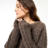 Sweater de punto con diseño trenzado, cuello redondo y mangas largas, de corte holgado y textura suave.