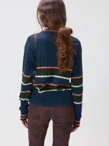 Sweater clásico de punto cable con cuello redondo a la base, mangas largas y fit al cuerpo. De color marrón con franjas horizontales violetas y amarillas, cuenta con el cuello, puños y ruedo acanalados, además de un pequeño logo bordado en el pecho.
