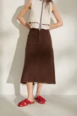 Falda larga de jean color marrón, de corte acampanado con costuras pespuntadas visibles y diseño de tiro medio.