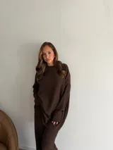 Buzo de cuello redondo y manga larga, confeccionado en tejido de viscosa con textura acanalada en color marrón chocolate. Presenta un corte holgado y relajado.