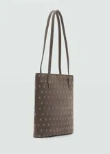 Bolso tipo tote de tamaño pequeño, confeccionado en piel bovina color marrón con diseño troquelado de ojales metálicos en toda su superficie. Cuenta con doble asa de hombro y forro interior de poliéster.