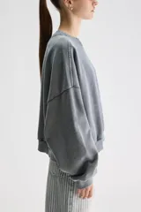 Buzo oversize gris de algodón con efecto acid wash, cuello redondo, hombros caídos, mangas largas y terminaciones acanaladas.