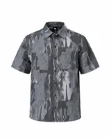 Camisa de manga corta con estampado abstracto en tonos grises, cuello clásico, bolsillos frontales aplicados y cierre frontal de botones a presión.